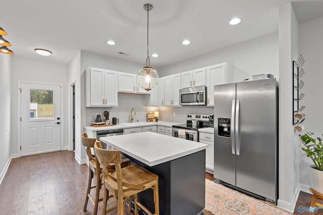 kitchen featuring pendant lighting, stainless steel appliances, wood-type flooring, and white cabinets