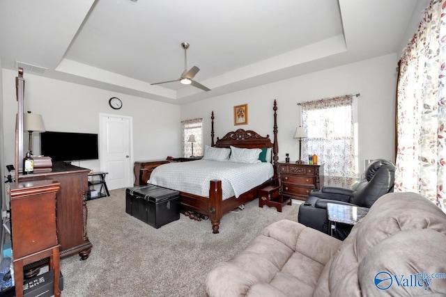 bedroom featuring carpet floors, a raised ceiling, visible vents, and ceiling fan