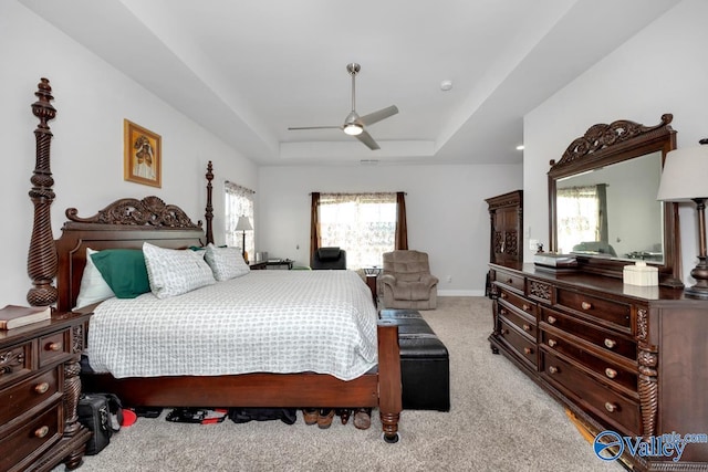 bedroom featuring ceiling fan, baseboards, a raised ceiling, and light colored carpet