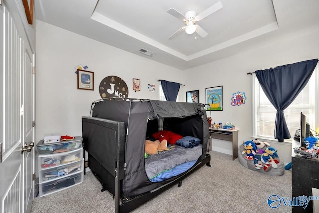 carpeted bedroom with a tray ceiling and visible vents