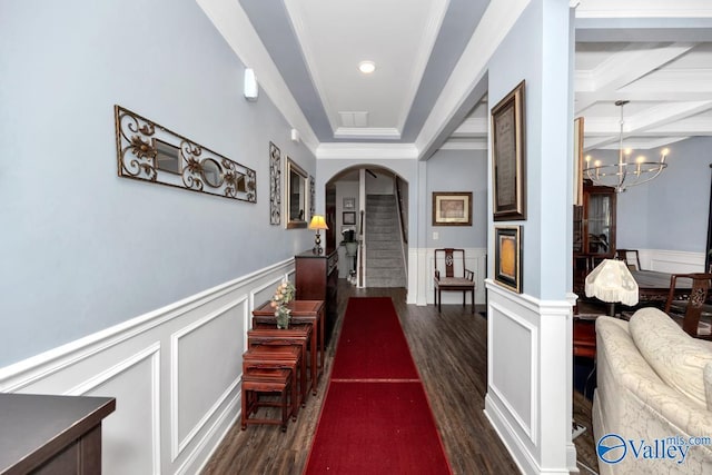 hallway with arched walkways, dark wood-style flooring, wainscoting, and crown molding