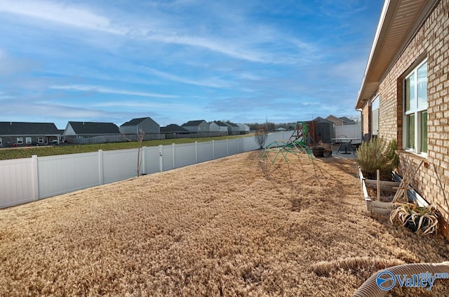 view of yard featuring a fenced backyard, a residential view, and a playground