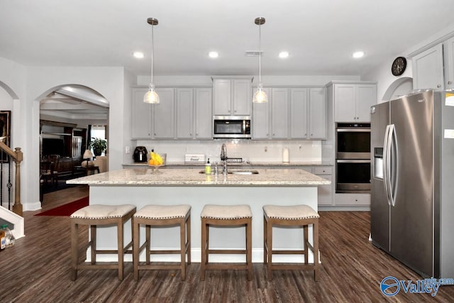 kitchen with stainless steel appliances, a sink, a kitchen island with sink, and pendant lighting