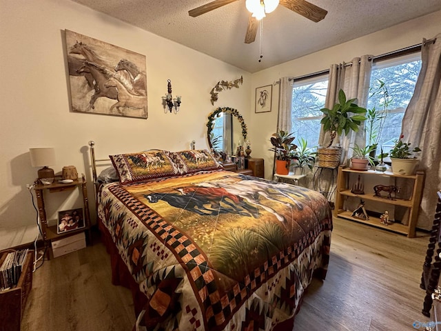 bedroom with hardwood / wood-style flooring, ceiling fan, and a textured ceiling