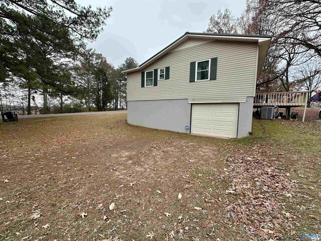 view of side of property featuring a garage, a deck, and central air condition unit