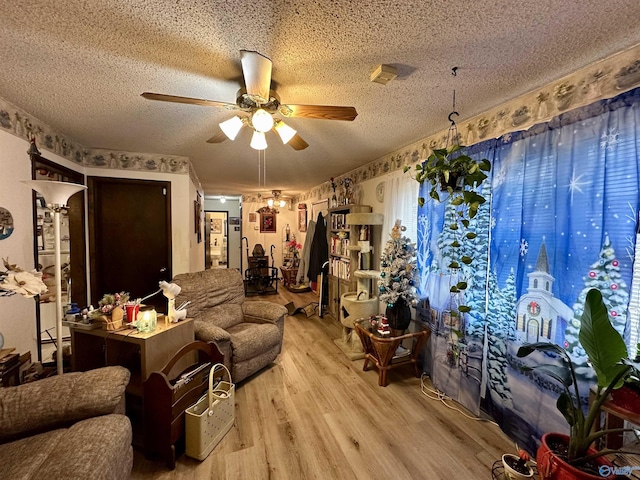 living room featuring ceiling fan, light hardwood / wood-style flooring, and a textured ceiling