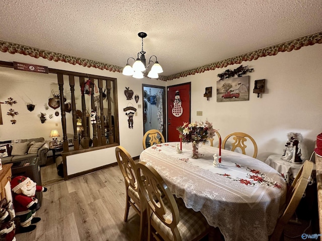 dining room with a chandelier, a textured ceiling, and light wood-type flooring