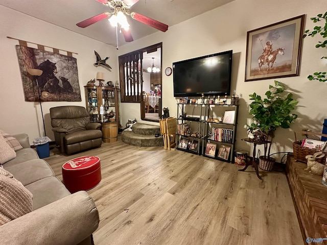 living room with ceiling fan with notable chandelier and light hardwood / wood-style floors