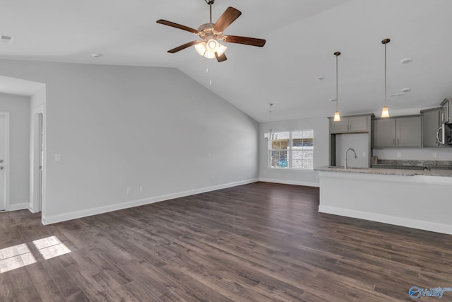 unfurnished living room featuring a sink, ceiling fan, baseboards, and dark wood-type flooring