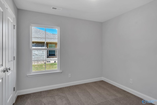 empty room featuring a wealth of natural light, baseboards, visible vents, and carpet flooring