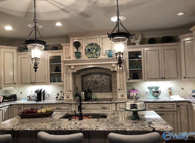 kitchen featuring pendant lighting, a kitchen breakfast bar, tasteful backsplash, and light stone countertops