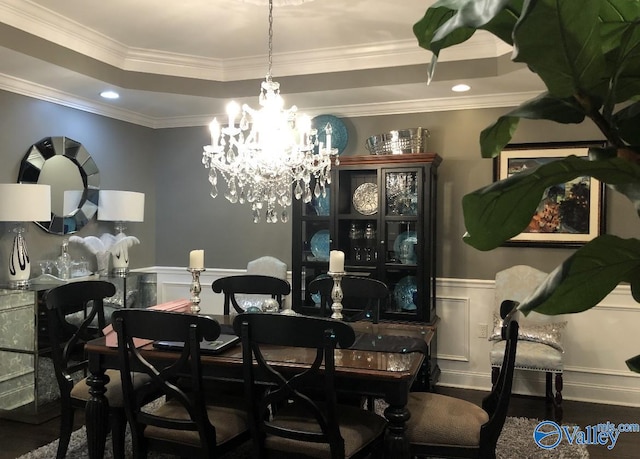 dining room featuring an inviting chandelier, a raised ceiling, and ornamental molding