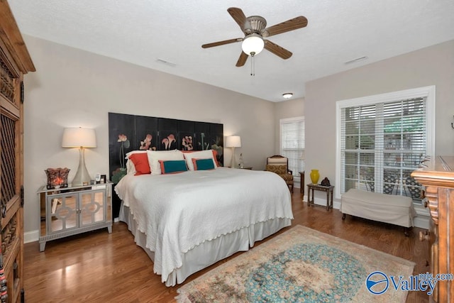 bedroom featuring dark wood-type flooring, a textured ceiling, and ceiling fan