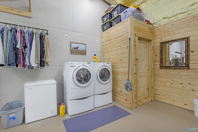 clothes washing area featuring washing machine and clothes dryer and wooden walls