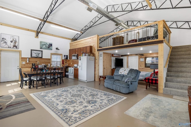 living room featuring concrete floors and high vaulted ceiling