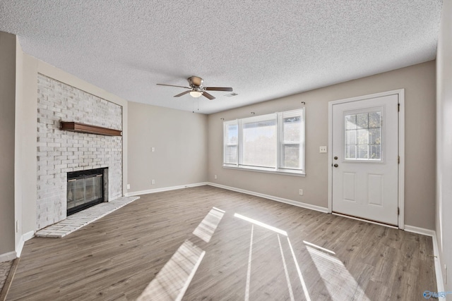 13935 SW Wyandotte Dr, Huntsville, AL 35803 - unfurnished living room featuring ceiling fan, wood finished floors, a textured ceiling, and a brick fireplace