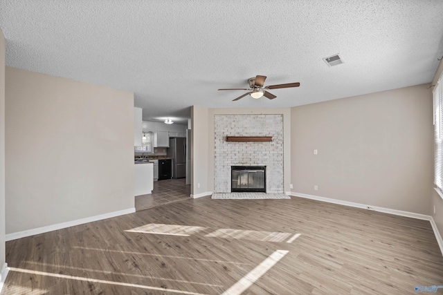 13935 SW Wyandotte Dr, Huntsville, AL 35803 - unfurnished living room with ceiling fan, light wood-style floors, a textured ceiling, and a fireplace