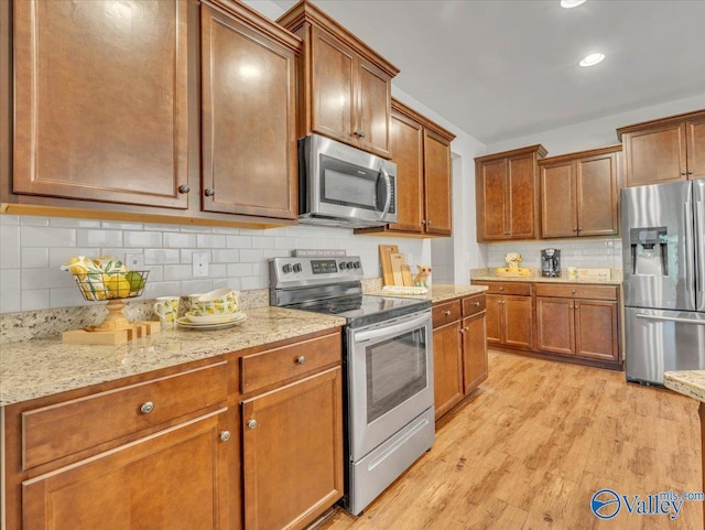 27004 Mill Creek Dr, Athens, AL 35613 - kitchen featuring appliances with stainless steel finishes, light stone counters, light wood finished floors, and tasteful backsplash
