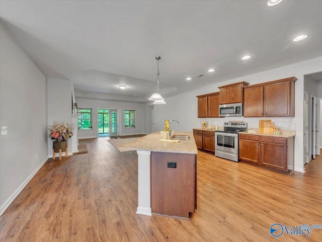 27004 Mill Creek Dr, Athens, AL 35613 - kitchen featuring brown cabinetry, a sink, open floor plan, light wood-style floors, and stainless steel appliances