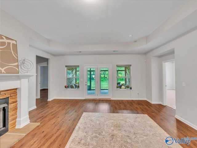 27004 Mill Creek Dr, Athens, AL 35613 - unfurnished living room featuring baseboards, wood finished floors, a tray ceiling, and a fireplace