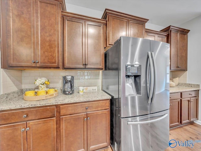 27004 Mill Creek Dr, Athens, AL 35613 - kitchen with stainless steel fridge, light stone counters, decorative backsplash, and light wood-type flooring