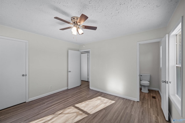 unfurnished bedroom featuring a textured ceiling, light hardwood / wood-style floors, ensuite bath, and ceiling fan