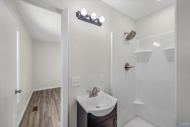 bathroom with a shower, hardwood / wood-style floors, and a textured ceiling