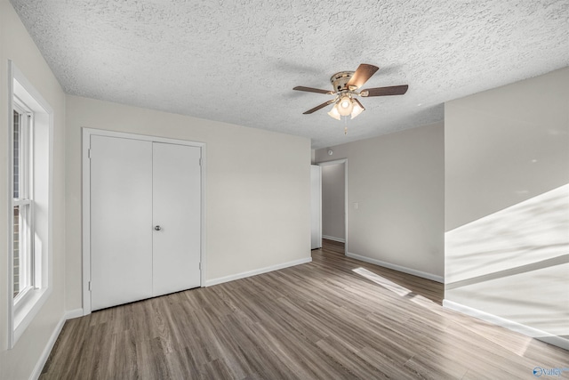 unfurnished bedroom featuring ceiling fan, a closet, hardwood / wood-style floors, and a textured ceiling