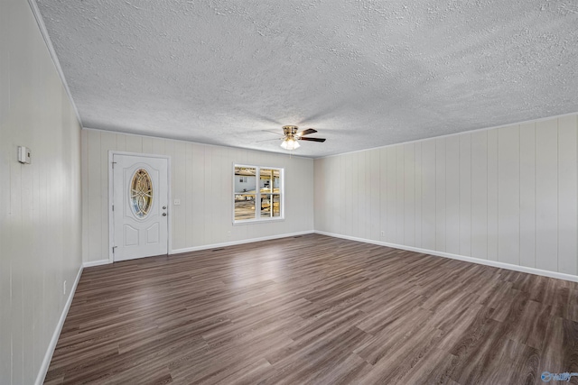 entrance foyer with ceiling fan, wood walls, and dark wood-type flooring