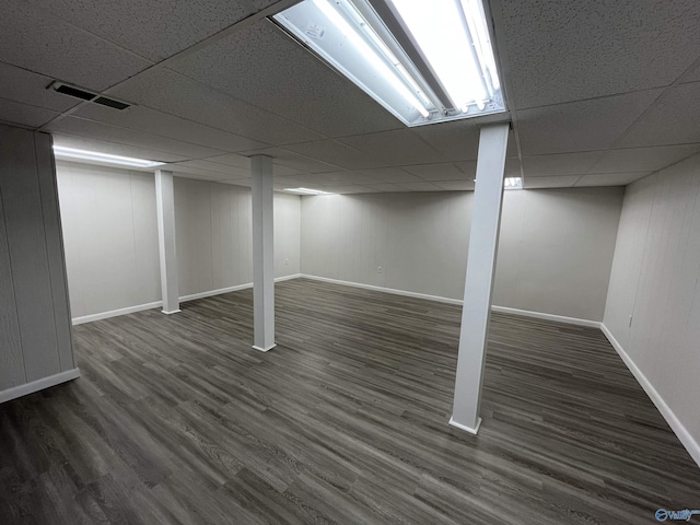 basement featuring a paneled ceiling and dark wood-type flooring