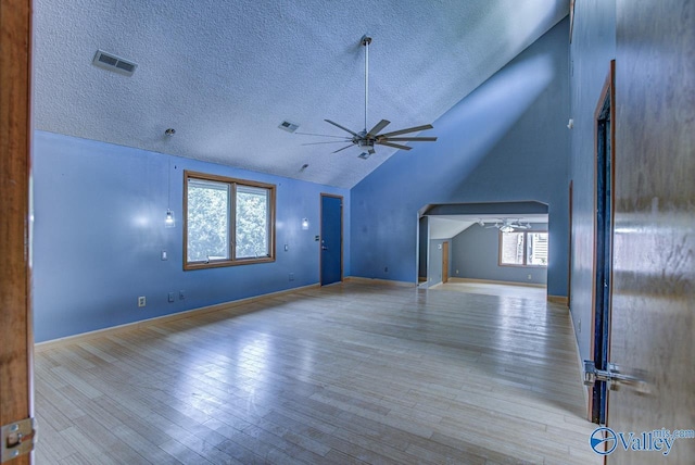 unfurnished living room with lofted ceiling, a textured ceiling, light hardwood / wood-style floors, and ceiling fan