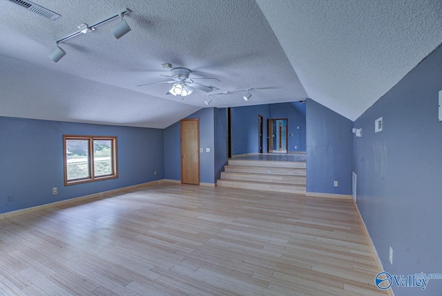 additional living space with lofted ceiling, a textured ceiling, light hardwood / wood-style flooring, and ceiling fan