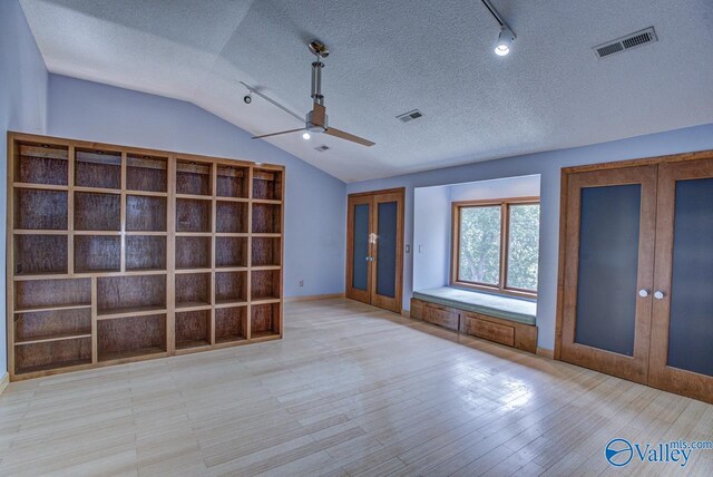 interior space featuring lofted ceiling, ceiling fan, light hardwood / wood-style floors, a textured ceiling, and french doors