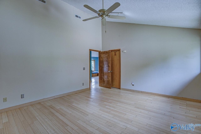 empty room featuring ceiling fan, high vaulted ceiling, a textured ceiling, and light wood-type flooring