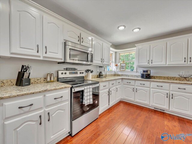 78 Bob Cir, Scottsboro, AL 35769 - kitchen with stainless steel appliances, white cabinets, light stone counters, light wood-type flooring, and recessed lighting