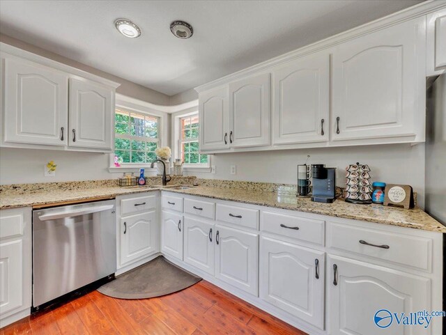 78 Bob Cir, Scottsboro, AL 35769 - kitchen with stainless steel dishwasher, light wood-style floors, white cabinetry, a sink, and light stone counters
