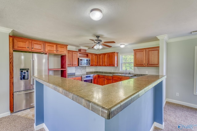 kitchen with crown molding, stainless steel appliances, light carpet, ceiling fan, and a peninsula