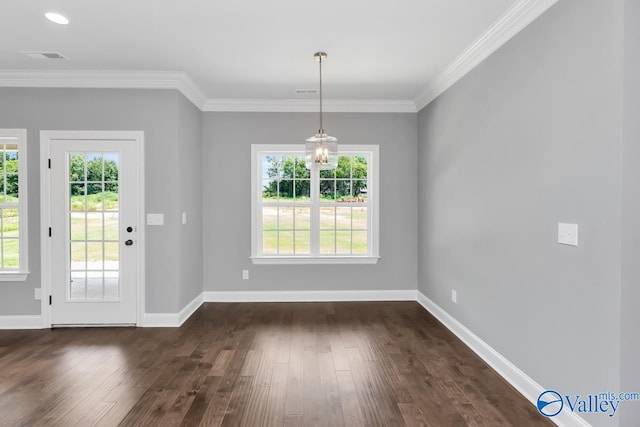 unfurnished dining area featuring dark wood-type flooring, plenty of natural light, crown molding, and a notable chandelier