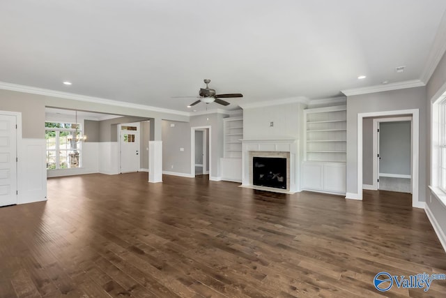 unfurnished living room featuring dark hardwood / wood-style flooring, built in shelves, ornamental molding, and ceiling fan with notable chandelier