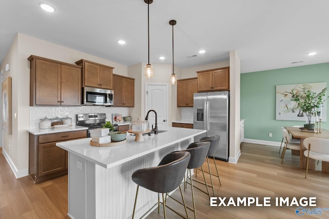 29555 Canoe Cir, Harvest, AL 35749 - kitchen with brown cabinets, stainless steel appliances, a sink, light wood-style floors, and a kitchen breakfast bar