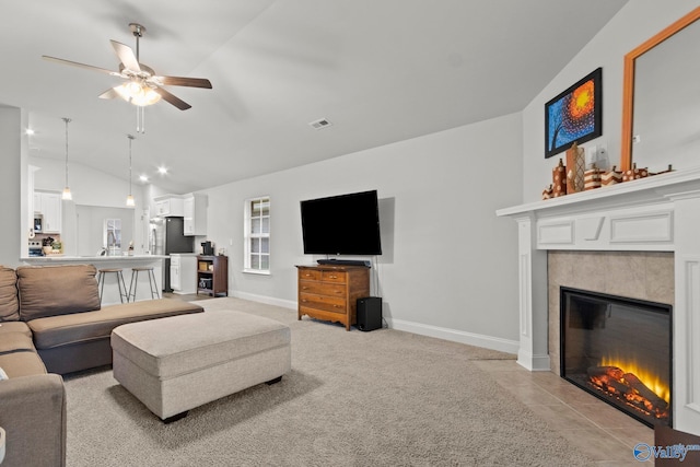 living room featuring a tile fireplace, light carpet, visible vents, baseboards, and vaulted ceiling