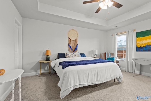 bedroom featuring carpet floors, a tray ceiling, a ceiling fan, and baseboards