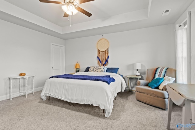 bedroom featuring a tray ceiling, carpet, visible vents, and baseboards