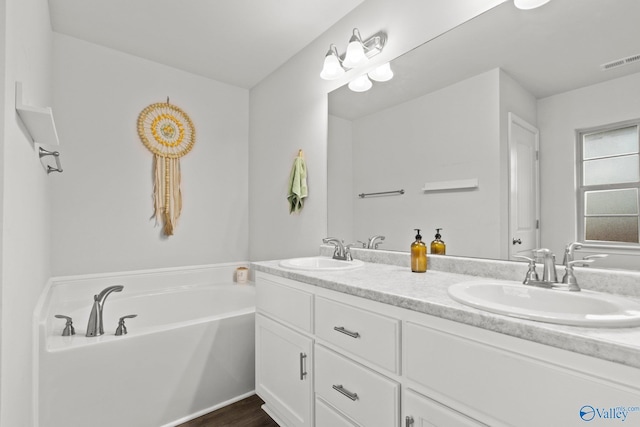 full bath featuring a bath, double vanity, a sink, and visible vents