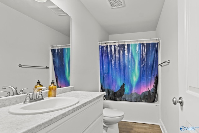 bathroom with toilet, vanity, wood finished floors, and visible vents