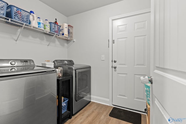 washroom with laundry area, light wood-style flooring, baseboards, and separate washer and dryer