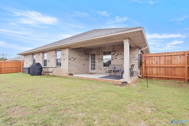 back of property featuring a patio, a fenced backyard, roof with shingles, a yard, and brick siding