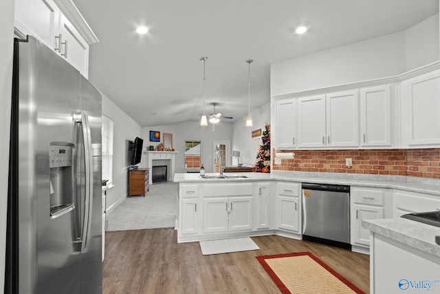 kitchen with a fireplace, lofted ceiling, appliances with stainless steel finishes, open floor plan, and a sink