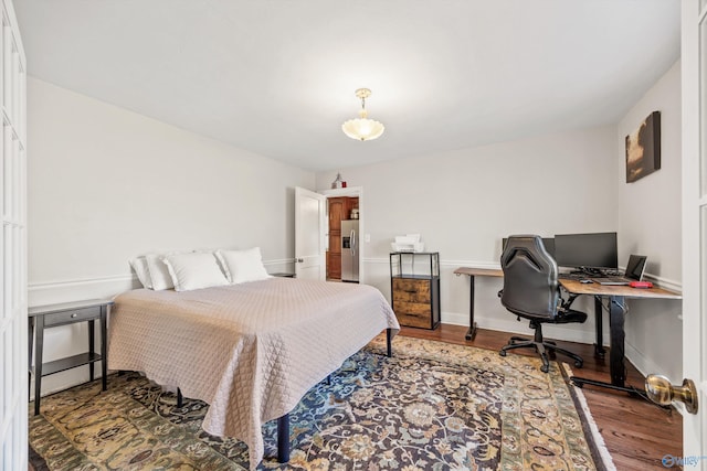 bedroom with stainless steel refrigerator with ice dispenser and wood-type flooring