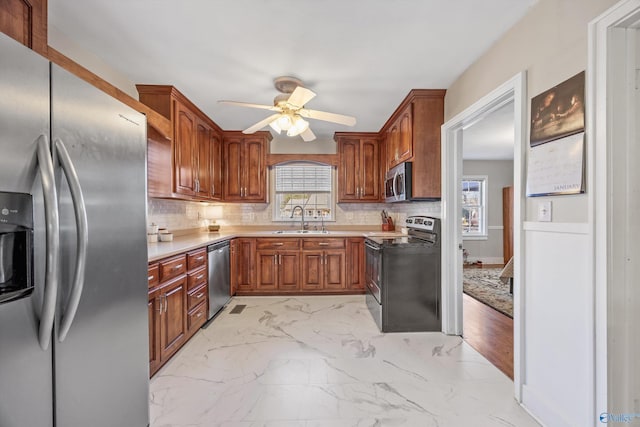 kitchen with sink, backsplash, ceiling fan, and appliances with stainless steel finishes